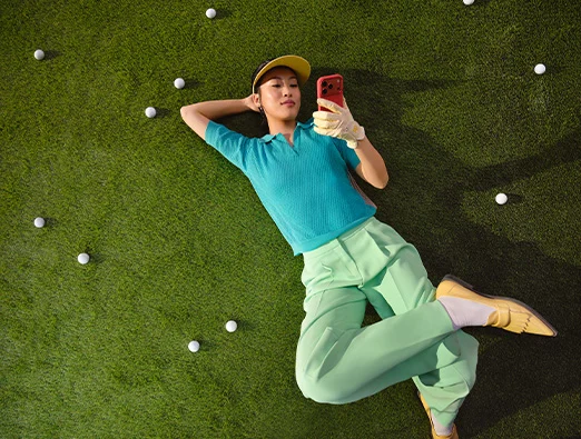 Person on a lawn looking at a smartphone.